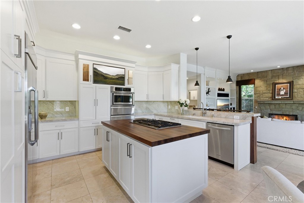 Remodeled kitchen featuring custom cabinetry, Taj Mahal quartzite countertops, stainless steel appliances, and a center - 31251 Calle Bolero, San Juan Capistrano CA 92675 - photo 15