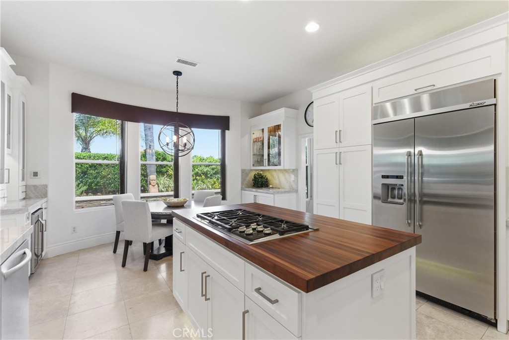Remodeled kitchen featuring custom cabinetry, Taj Mahal quartzite countertops, stainless steel appliances, and a center - 31251 Calle Bolero, San Juan Capistrano CA 92675 - photo 17