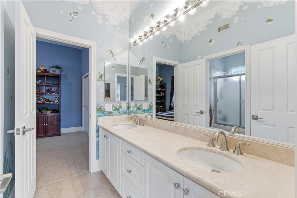 Secondary bathroom with dual vanities, spacious countertops, and functional access connecting the adjoining bedrooms - 31251 Calle Bolero, San Juan Capistrano CA 92675 - photo 38