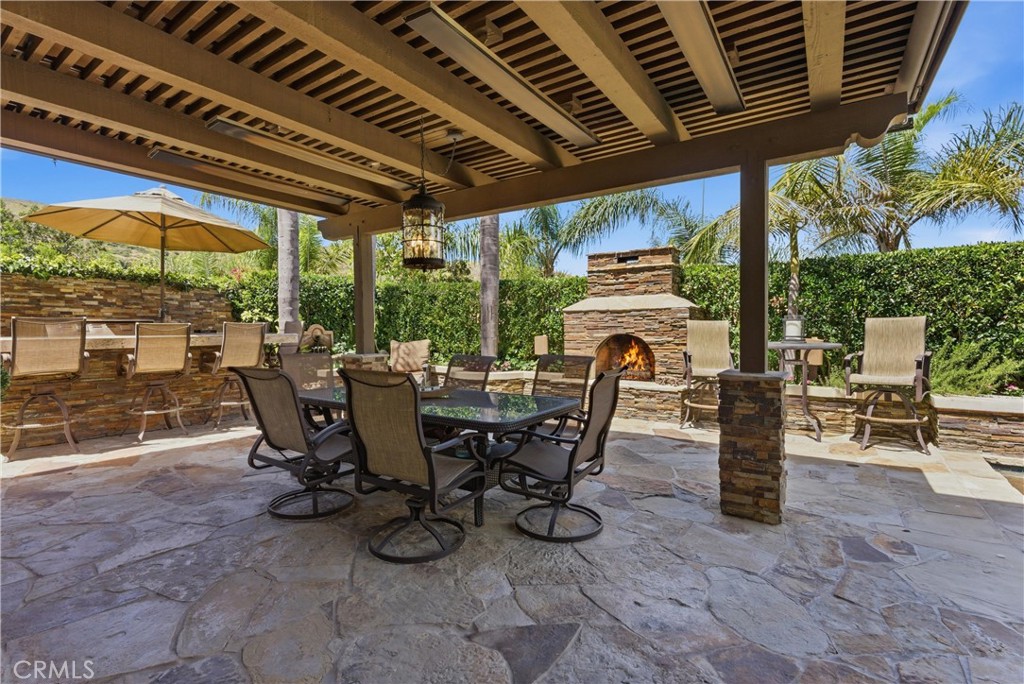 Covered outdoor entertaining area, a stone fireplace, and multiple seating spaces - 31251 Calle Bolero, San Juan Capistrano CA 92675 - photo 44