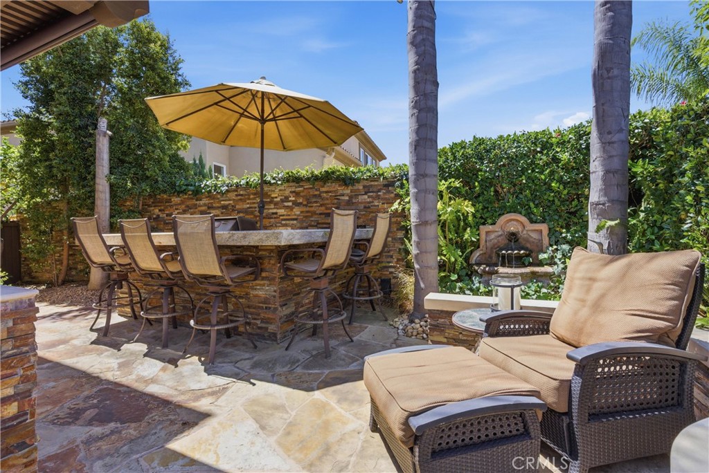 Private outdoor retreat with elevated bar seating, a built-in BBQ, lush tropical landscaping, and tranquil fountain acce - 31251 Calle Bolero, San Juan Capistrano CA 92675 - photo 46