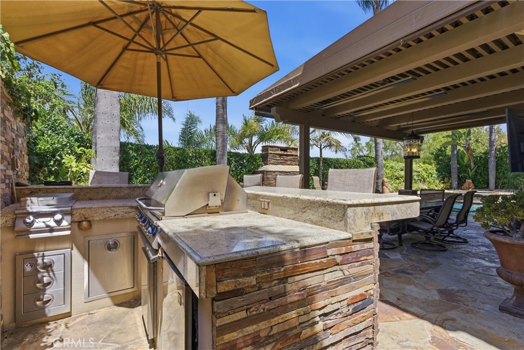 Private outdoor retreat with elevated bar seating, a built-in BBQ, lush tropical landscaping, and tranquil fountain acce - 31251 Calle Bolero, San Juan Capistrano CA 92675 - photo 47