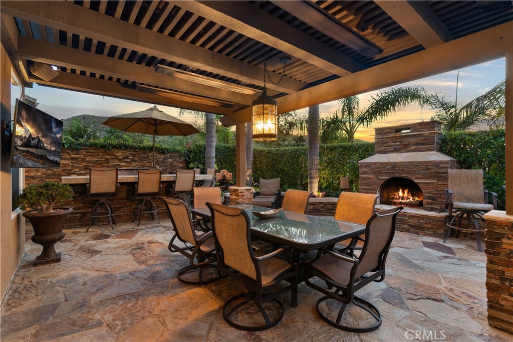 Covered outdoor entertaining area, a stone fireplace, and multiple seating spaces - 31251 Calle Bolero, San Juan Capistrano CA 92675 - photo 53