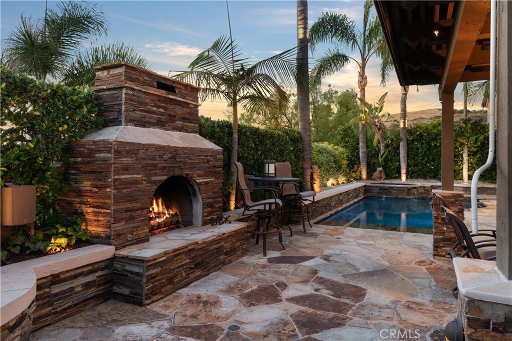 Covered outdoor entertaining area, a stone fireplace, and multiple seating spaces - 31251 Calle Bolero, San Juan Capistrano CA 92675 - photo 55