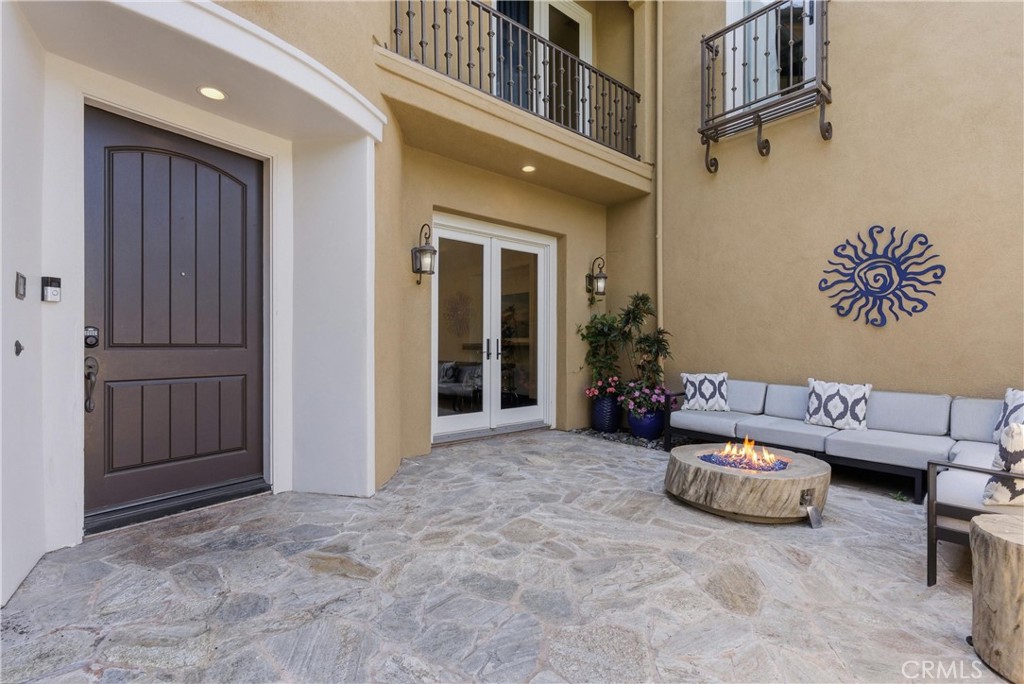 Private front courtyard entry with natural stone flooring, outdoor lounge seating, gas fire feature, covered patio, and - 31491 Carril De Maderas, San Juan Capistrano CA 92675 - photo 3