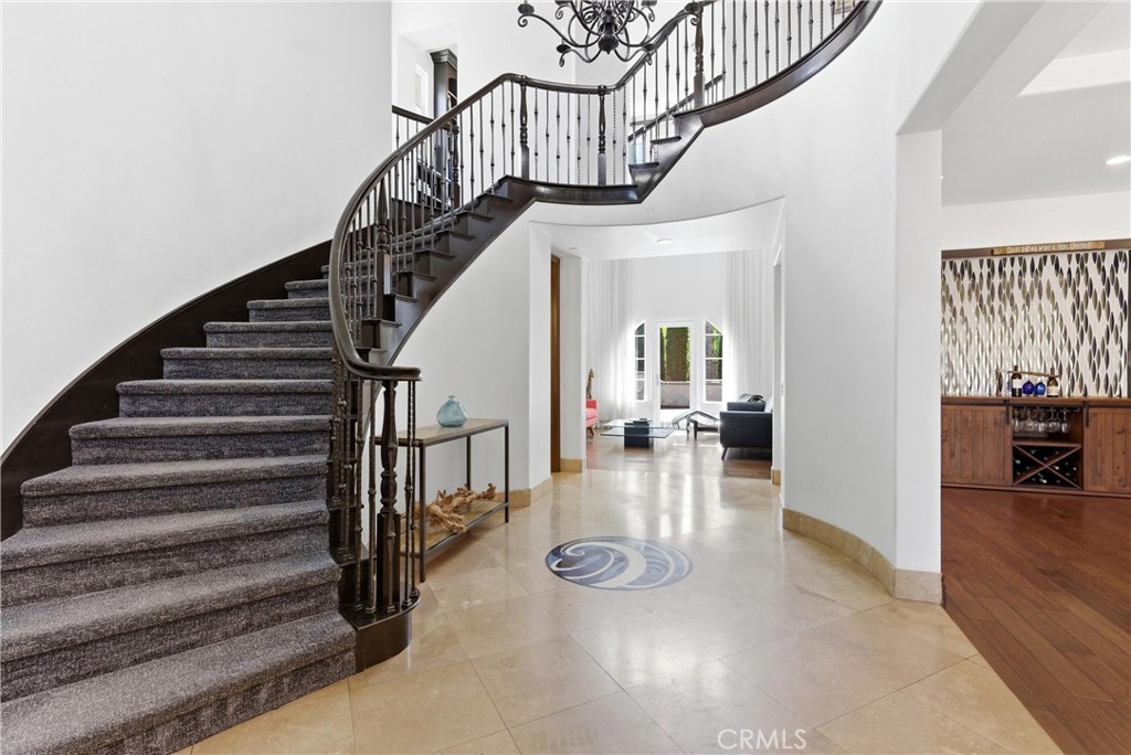 Grand foyer entrance with sweeping curved staircase, wrought iron balusters, soaring ceilings, travertine flooring, and - 31491 Carril De Maderas, San Juan Capistrano CA 92675 - photo 4
