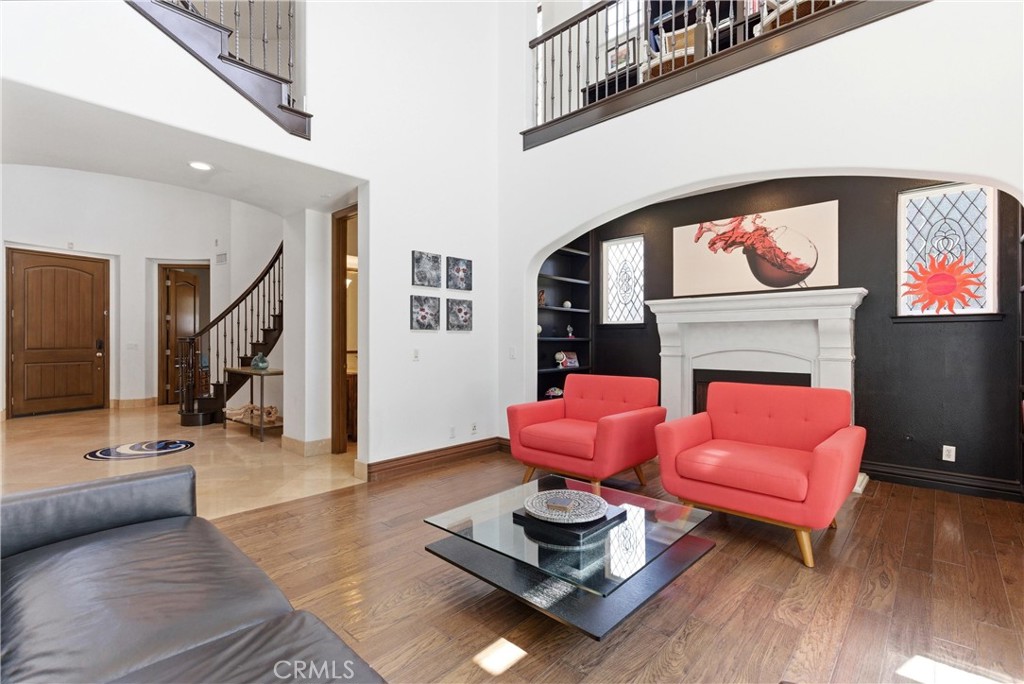 Open-concept formal living area featuring soaring ceilings, rich hardwood flooring, custom built-ins, oversized windows, - 31491 Carril De Maderas, San Juan Capistrano CA 92675 - photo 7