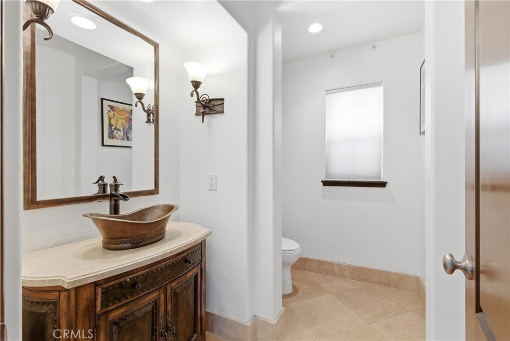 Custom powder room with furniture-style vanity, vessel sink, stone countertop, designer lighting, and travertine floorin - 31491 Carril De Maderas, San Juan Capistrano CA 92675 - photo 10