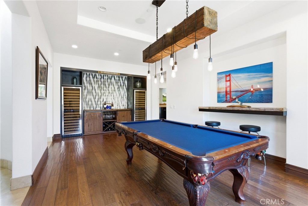 Entertainer’s game room with billiards area, custom wet bar, dual wine refrigerators, hardwood flooring, designer lighti - 31491 Carril De Maderas, San Juan Capistrano CA 92675 - photo 11