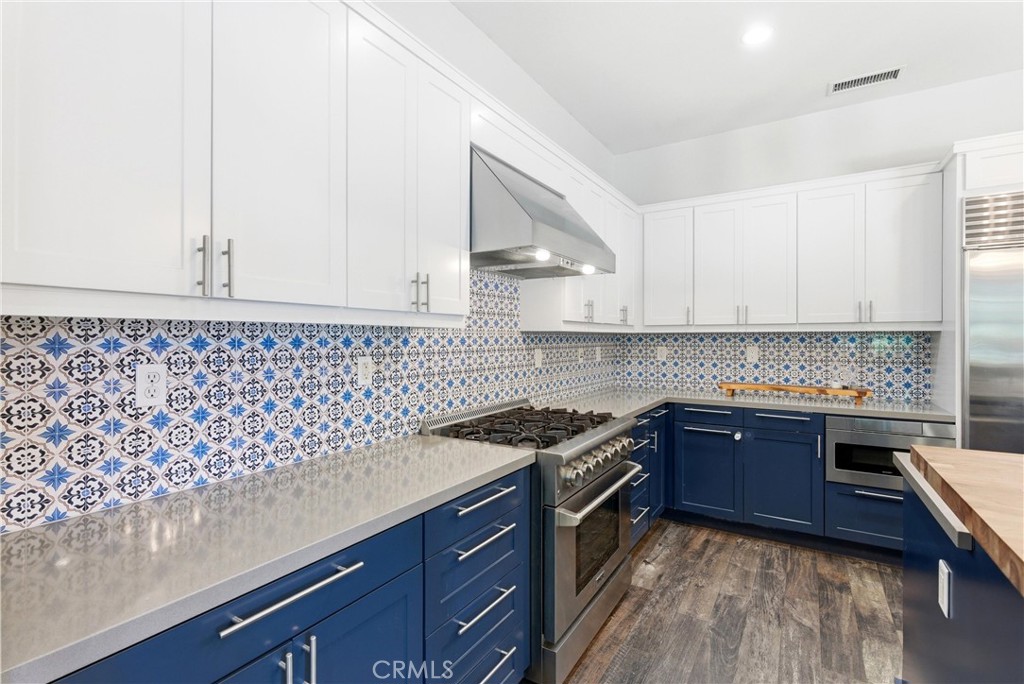 Designer kitchen with custom patterned tile backsplash, quartz counters, six-burner gas range, stainless steel hood, and - 31491 Carril De Maderas, San Juan Capistrano CA 92675 - photo 21