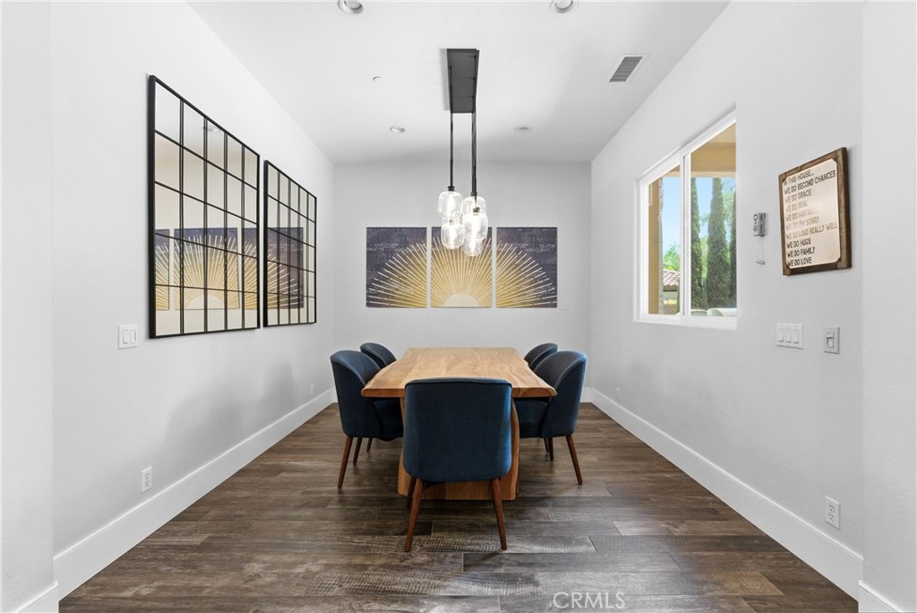 Modern dining area featuring custom lighting, live-edge wood dining table, contemporary finishes, and open flow to the r - 31491 Carril De Maderas, San Juan Capistrano CA 92675 - photo 23