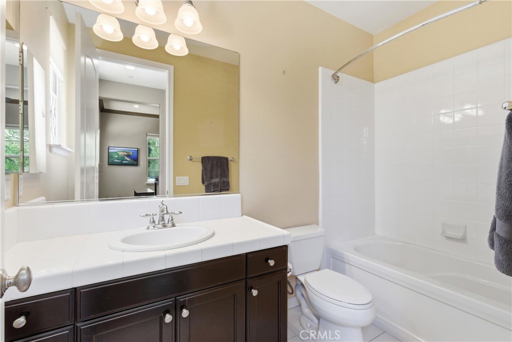 Main level guest bathroom featuring a tub and shower combination, oversized vanity mirror, and neutral finishes adjacent - 31491 Carril De Maderas, San Juan Capistrano CA 92675 - photo 36