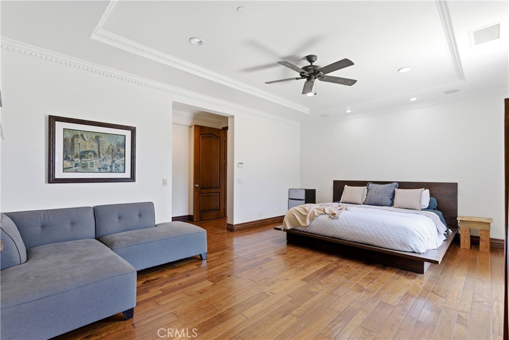 Spacious primary suite retreat featuring hardwood flooring, crown molding, recessed lighting, ceiling fan, and a dedicat - 31491 Carril De Maderas, San Juan Capistrano CA 92675 - photo 42