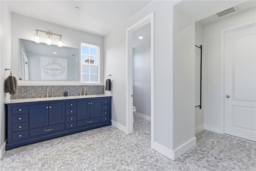 Expansive primary bathroom with oversized dual-sink navy vanity, marble-style countertops, designer hexagon tile floorin - 31491 Carril De Maderas, San Juan Capistrano CA 92675 - photo 49