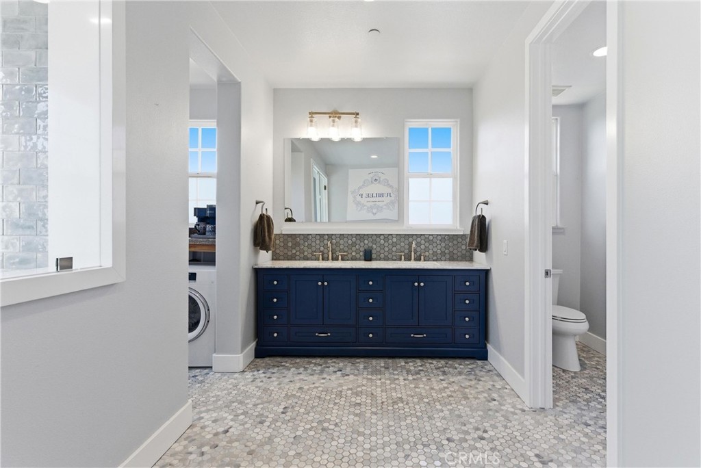 Primary bathroom vanity area showcasing custom blue cabinetry, dual sinks, designer tile backsplash, separate water clos - 31491 Carril De Maderas, San Juan Capistrano CA 92675 - photo 50