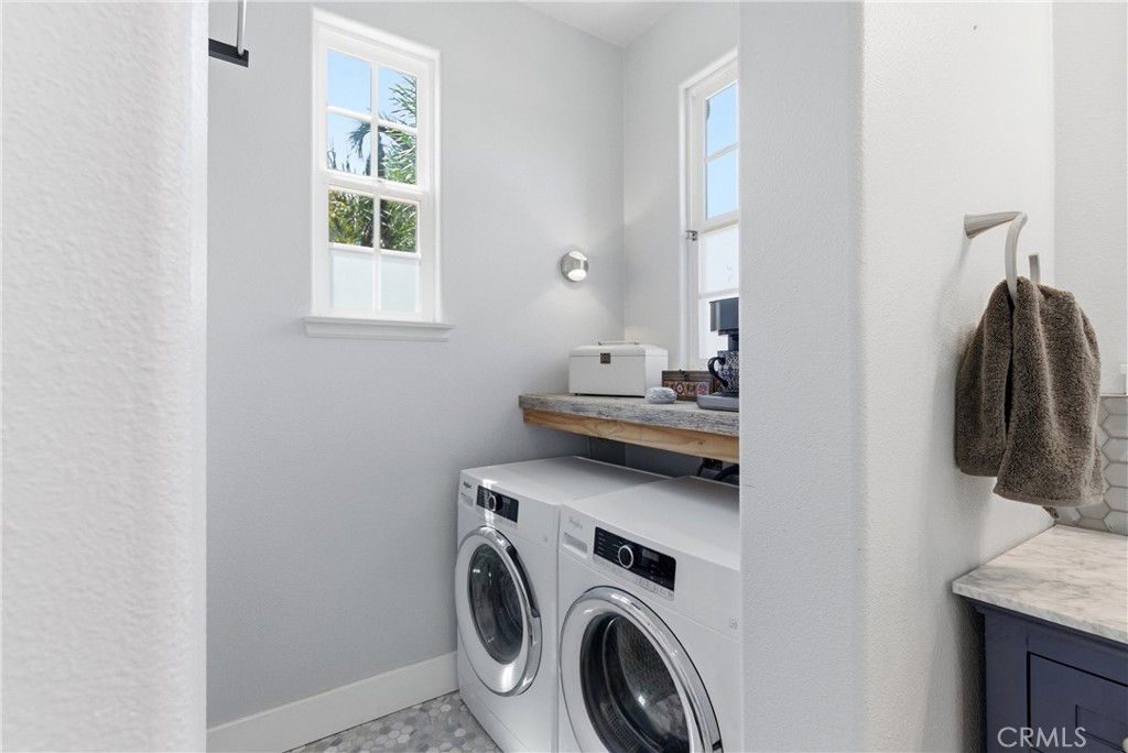 Spacious upstairs laundry room with side-by-side washer and dryer, natural light, custom countertop workspace, and adjac - 31491 Carril De Maderas, San Juan Capistrano CA 92675 - photo 52