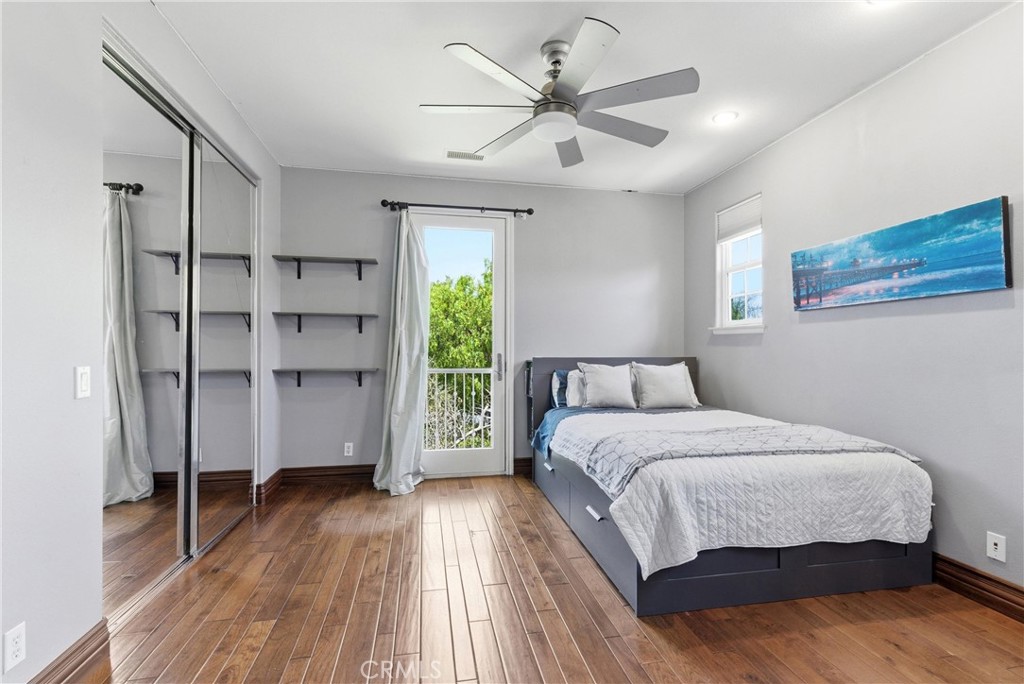 Bright upstairs guest bedroom with hardwood flooring, mirrored closet doors, built-in shelving, and private balcony acce - 31491 Carril De Maderas, San Juan Capistrano CA 92675 - photo 54