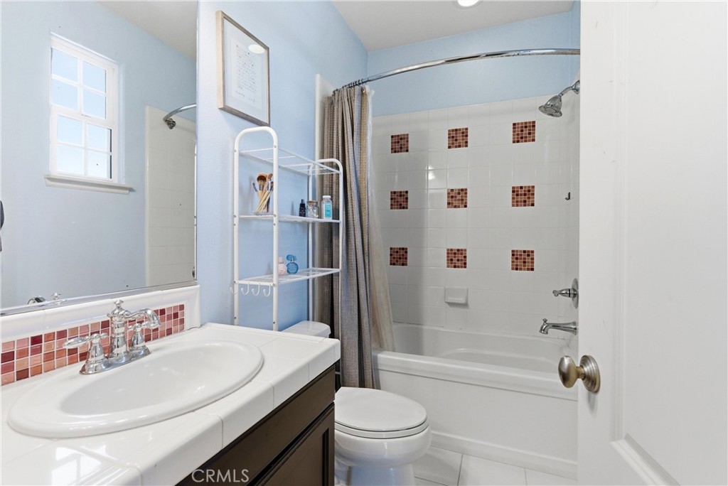 Additional full bathroom with blue accent walls, white tile vanity, tub/shower combination, and decorative tile accents. - 31491 Carril De Maderas, San Juan Capistrano CA 92675 - photo 63