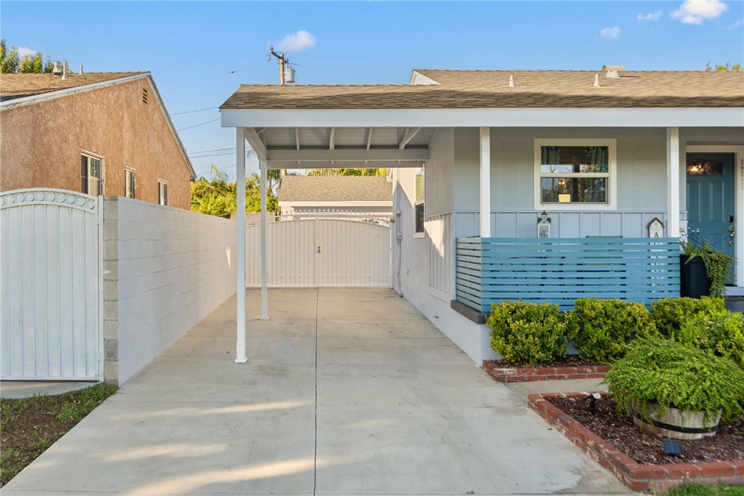 Covered carport with a long driveway leading to gated backyard entrance. - 1711 W 21st, Santa Ana CA 92706 - photo 4