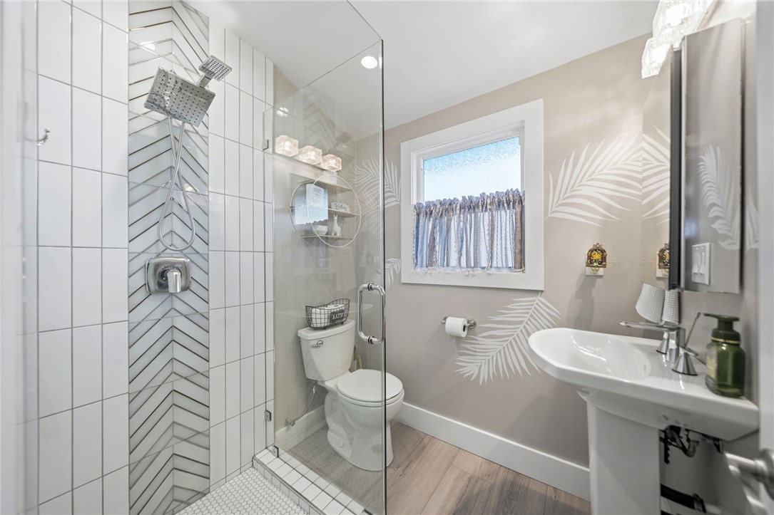Remodeled bathroom includes floor-to-ceiling tile with a chevron accent, a hexagon mosaic shower floor, and a frameless - 1711 W 21st, Santa Ana CA 92706 - photo 19