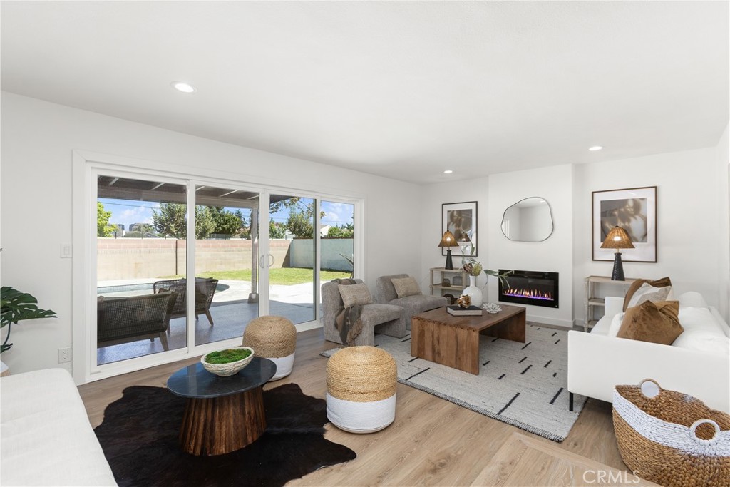 Living room with modern electric fireplace and direct access to outdoor patio and pool area - 3709 S Olive Street, Santa Ana CA 92707 - photo 23