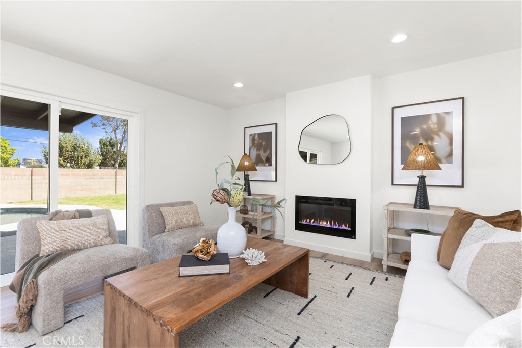 Living room with modern electric fireplace and direct access to outdoor patio and pool area - 3709 S Olive Street, Santa Ana CA 92707 - photo 26