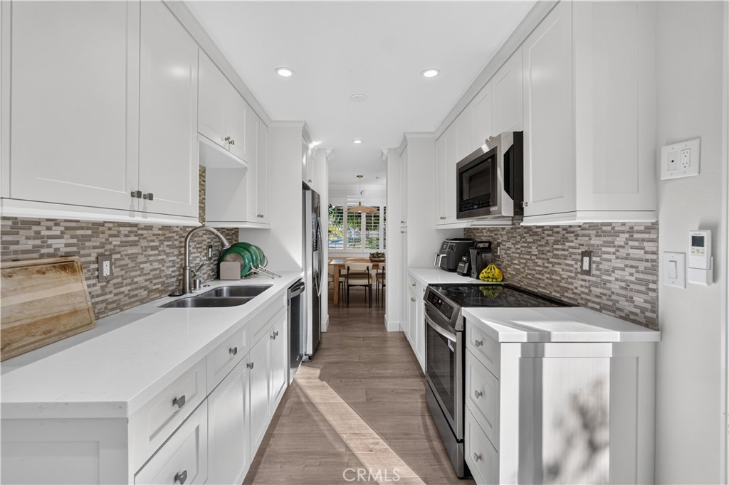 Galley kitchen has newer cabinets, quartz counters, electric range, microwave, dishwasher and refrigerator. - 12200 Montecito Road B112, Seal Beach CA 90740 - photo 7