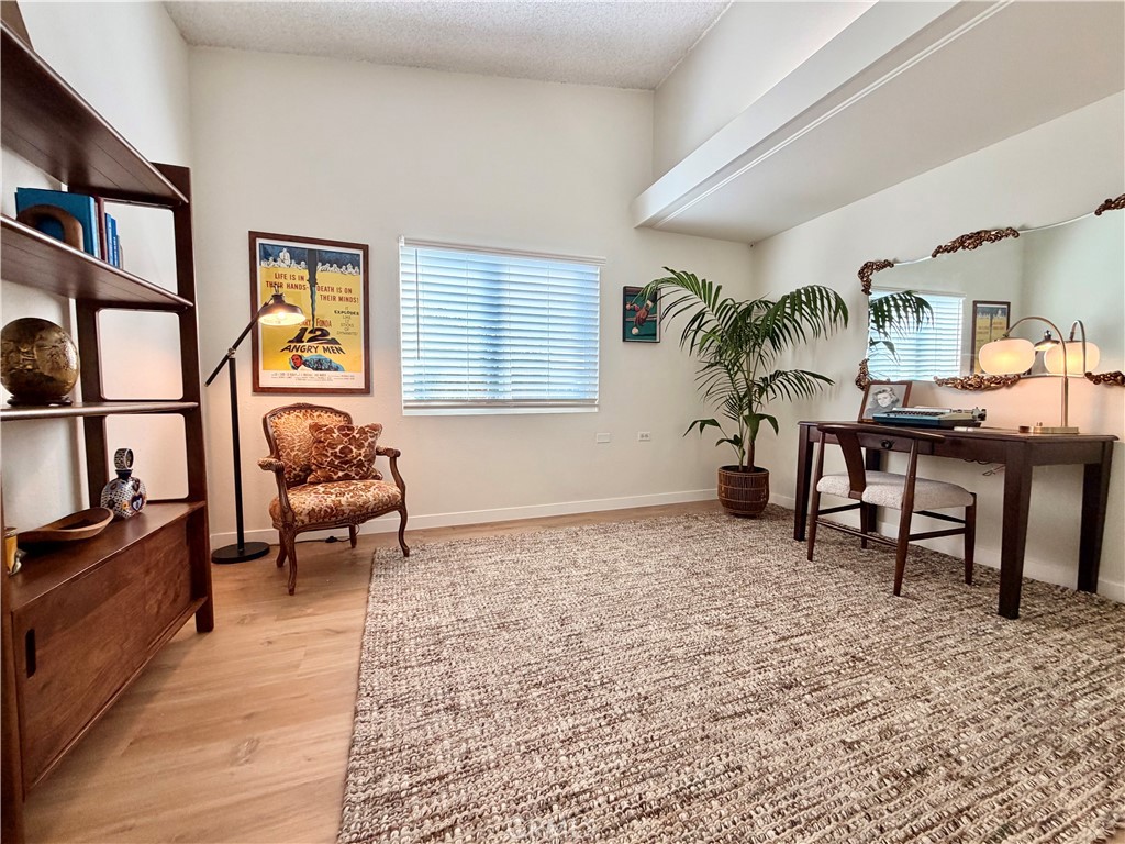 Comfortable bedroom/office with vaulted ceilings, large windows, and a peaceful atmosphere. - 13560 Medinac Lane 102 L, Seal Beach CA 90740 - photo 11