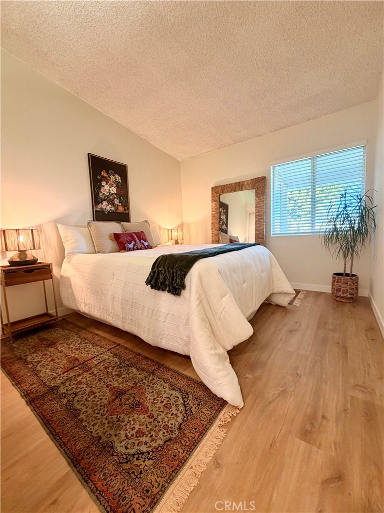 Primary bedroom with natural light, hardwood flooring, and ample space for furnishings. - 13560 Medinac Lane 102 L, Seal Beach CA 90740 - photo 14