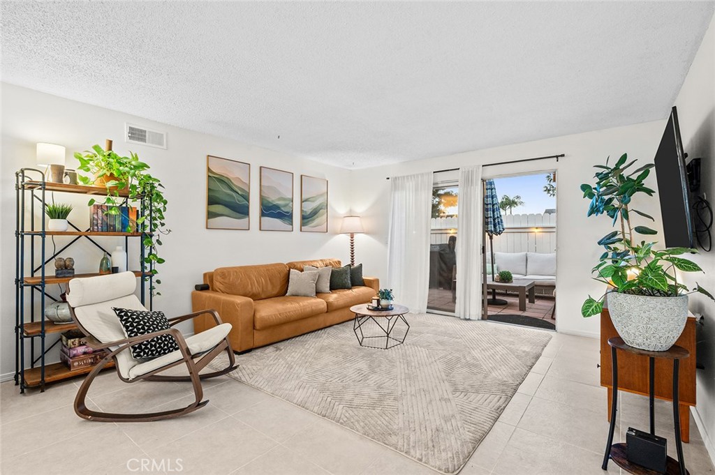 Bright living room with tile flooring and patio access. - 1881 Mitchell Avenue 135, Tustin CA 92780 - photo 1