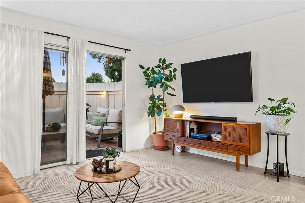 Bright living room with tile flooring and patio access. - 1881 Mitchell Avenue 135, Tustin CA 92780 - photo 16