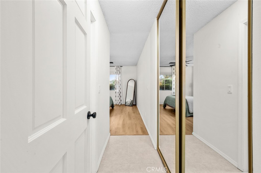 Hallway with mirrored closet doors leading into the bedroom. - 1881 Mitchell Avenue 135, Tustin CA 92780 - photo 20