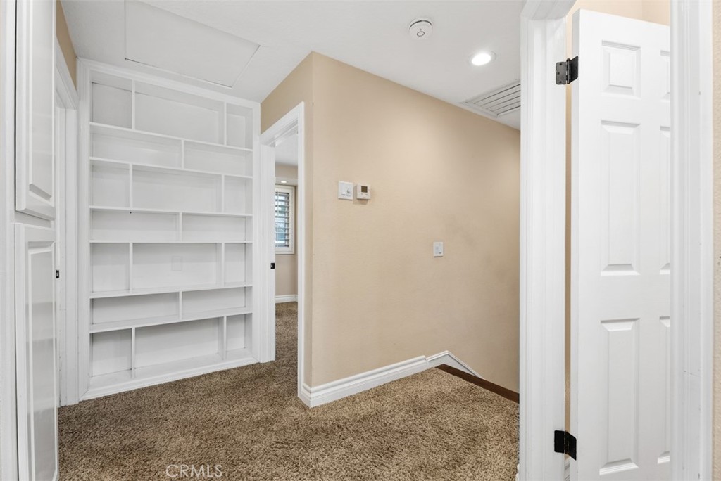Upstairs landing has carpet and a built in bookcase. Note above the stairs is the whole house fan keeping the house cool - 21674 Calle Alcazar, Yorba Linda CA 92887 - photo 18