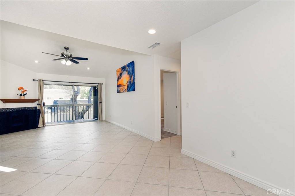 The living room has high ceiling with tile flooring, ceiling fan and the recess ceiling lights. The door on the right si - 23472 Cambridge Road 297, Yorba Linda CA 92887 - photo 4